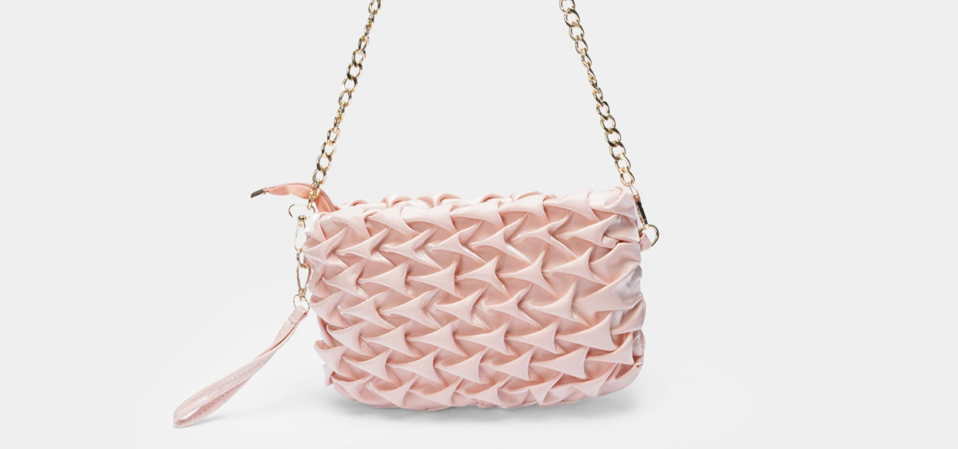 Pink woven handbag with a chain strap on a light pink background
